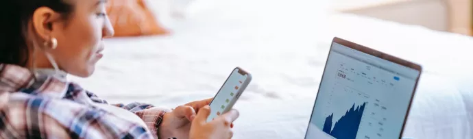 Stock image of person on phone with computer screen in front of her