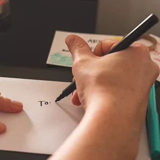 Image of hand which is writing an address on an envelope