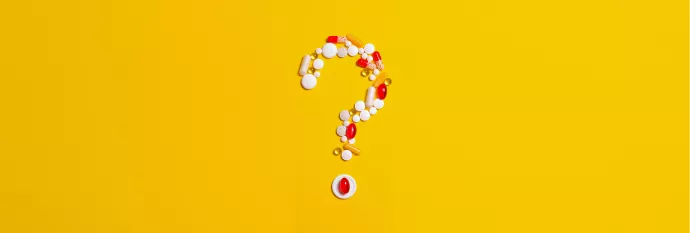 Various shaped pills arrange in a question mark on a yellow background