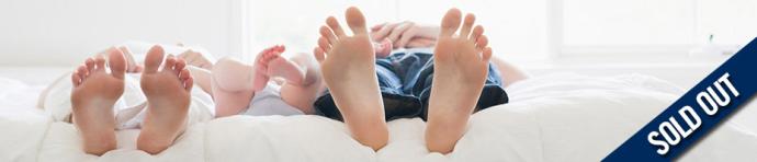 pairs of feet at the edge of a white bed with text overlay "sold out"
