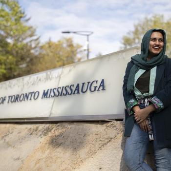 Amna Adnan sits in front of the "University of Toronto Mississauga side" outside of campus