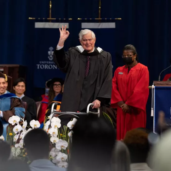 John Bond flashes an "okay sign" as he walks across the stage during Convocation 