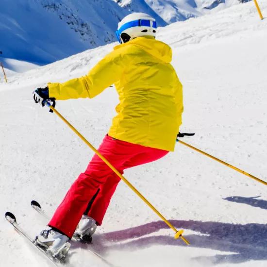 person in red pants and yellow jacket skiing