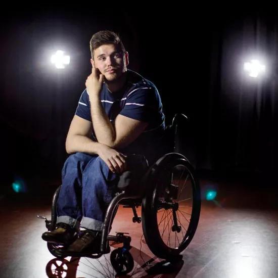 George Alevizos sitting in a wheelchair on center stage