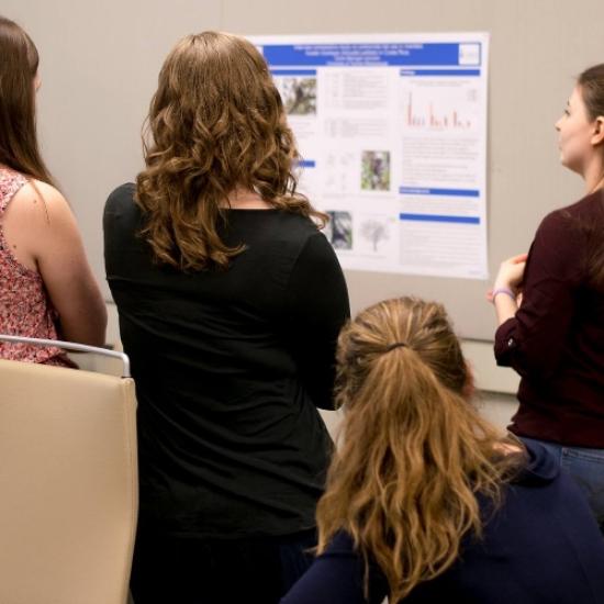 students view a research poster. Photo credit W. Aumeerally, Black n Orange photography.