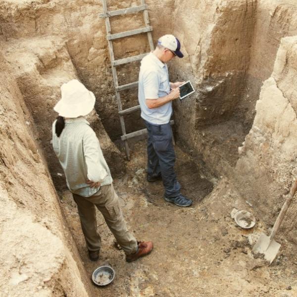 Two archaeologists standing in an excavated archaeological site. Photo © G. Crawford.