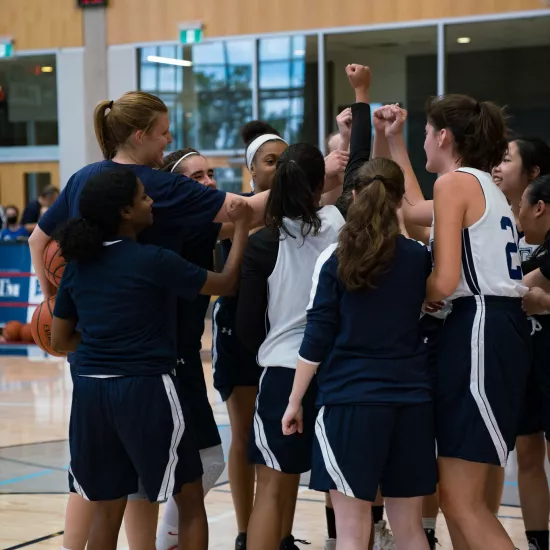 group of female basketball players in a huddle 