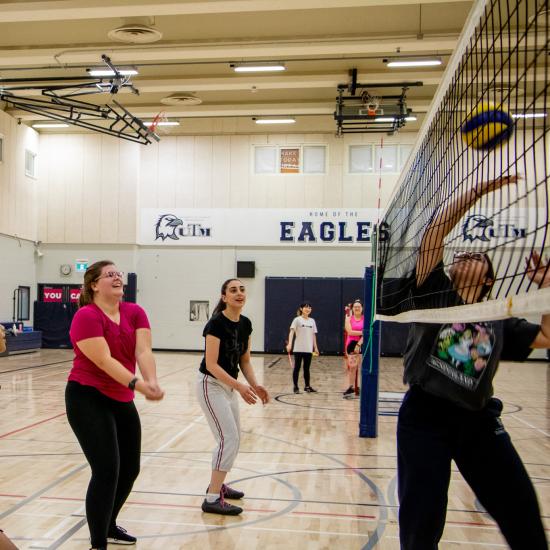 Group of women playing volleyball in an indoor gym court