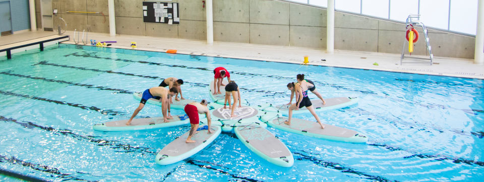 Group fitness on pool with stand up paddleboards