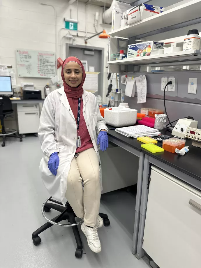 Areej Al-Dailami in lab coat seating, in lab