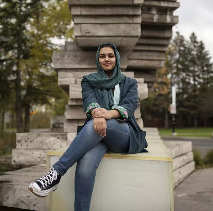 UTM Alumnus Amna Adnan, seated outside on the UTM campus