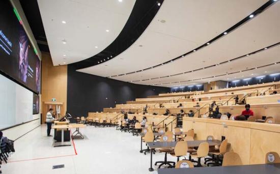 Interior of lecture hall with speaker and physically distanced students