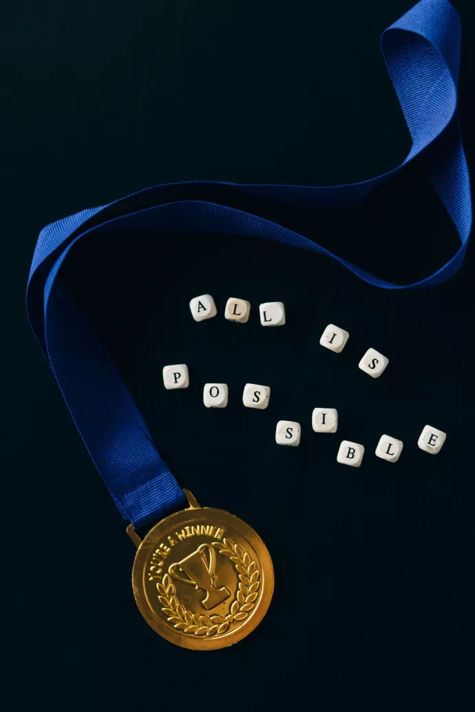 A medal with tiles that spell out "All is possible."