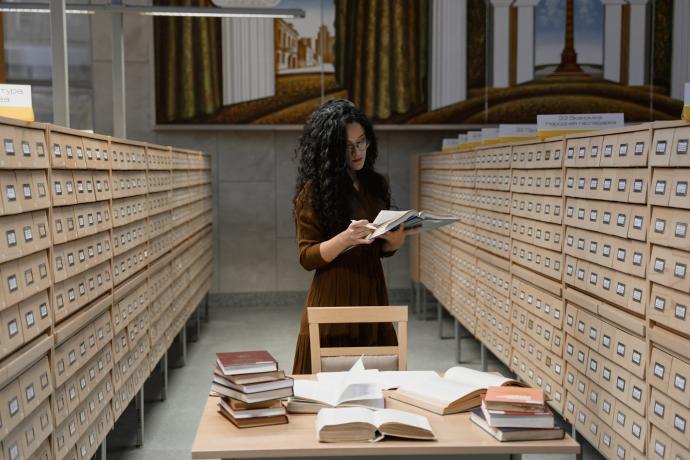 Photo of a person in a library setting surrounded by card catalogues