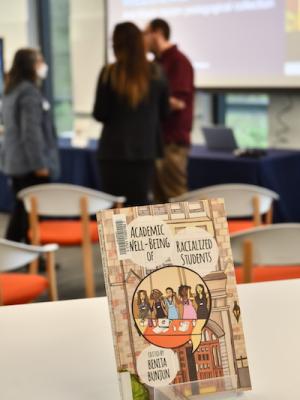 Book cover for Academic Well-Being of Racialized Students edited by Bunita Bunjun. Rob Makinson, Corrine Bent-Womack, and ISUP staff member Anne Gagné are in the background.