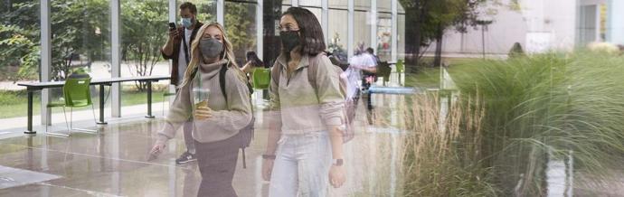 Two students walking on the UTM campus, wearing masks