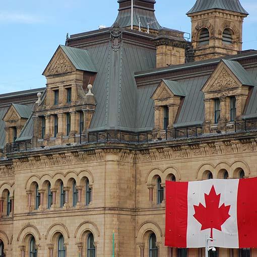 Exterior of Parliament building and Canadian flag in Ottawa. Photo by Chelsea Faucher on Unsplash