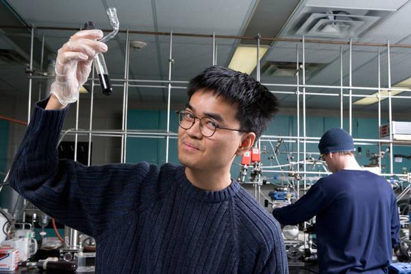Photo of of Neilson in the lab holding up a test tube 