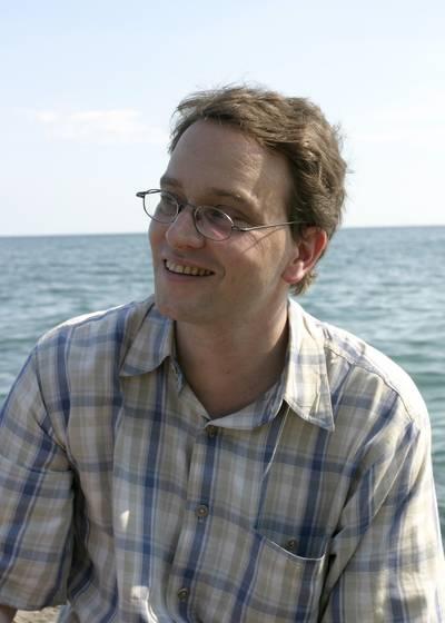 Photo of Ulrich Fekl smiling with a body of water in the background