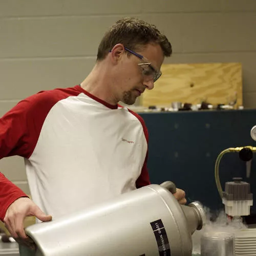 Photo of Dan pouring liquid nitrogen out from a big container into a beaker.