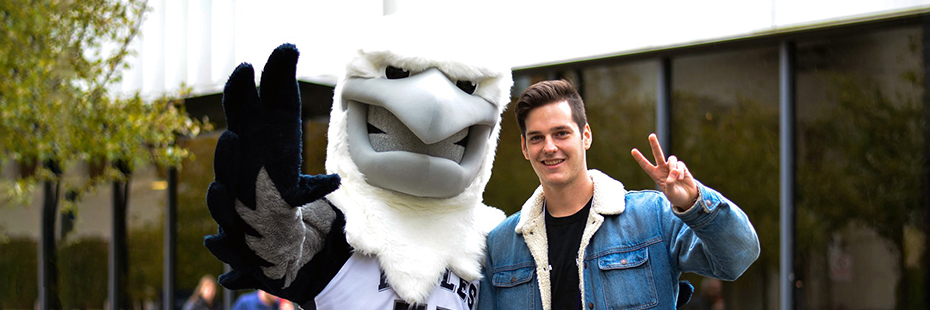 Student posing with the UTM Eagle Mascot