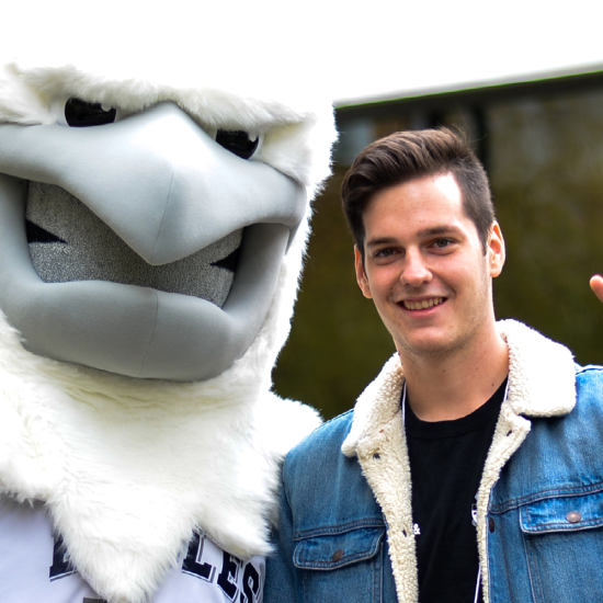 Student posing with UTM Eagle