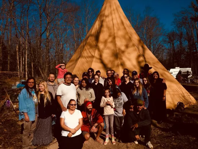 student smiling in front of a tipi