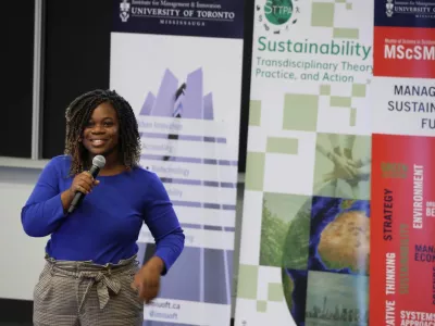 woman with microphone in front of sustainability banner