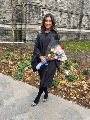 Farhana in black graduation robes with flowers