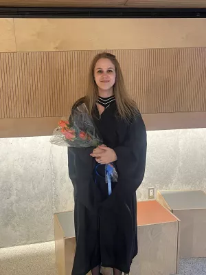 Laura in graduation robes holding flowers