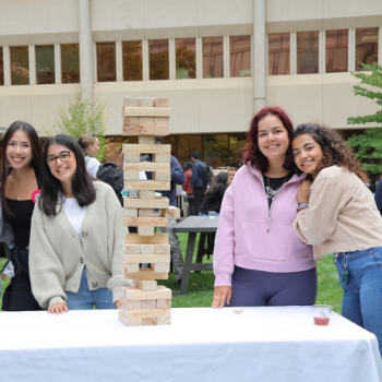Four students standing around a block of jenga