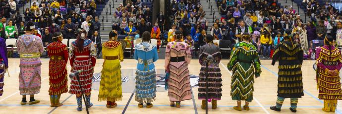 A line of dancers in colourful powwow regalia