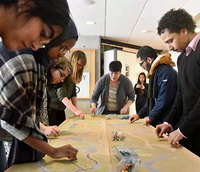 Group of students and leader work on a collaborative, Indigenous-inspired piece of artwork