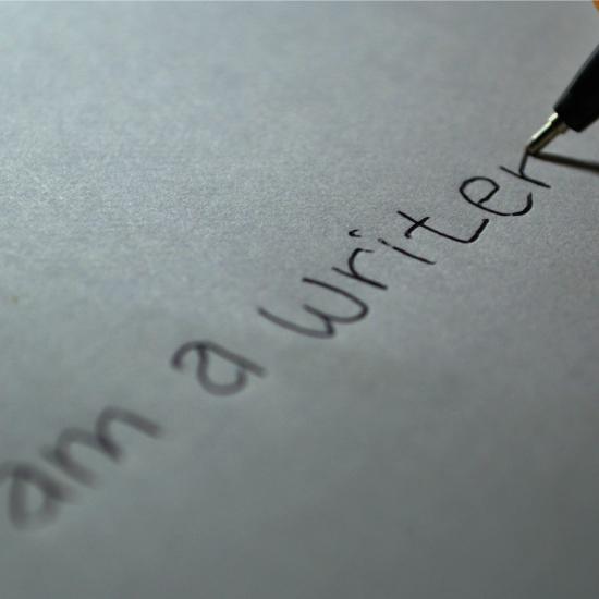 The phrase "I am a writer" being written by pen.
