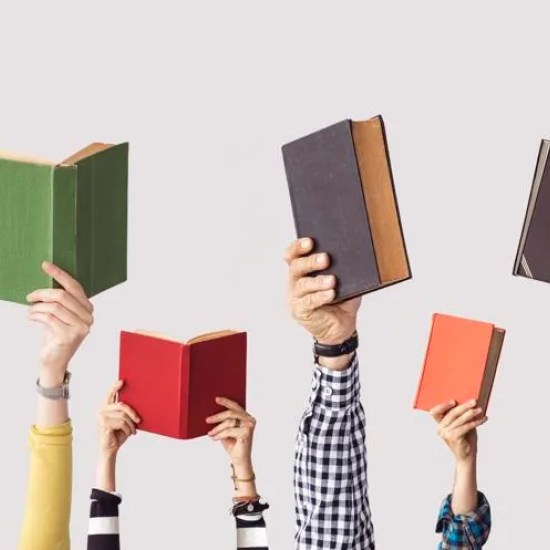 Multiple hands holding up books, forming a row.
