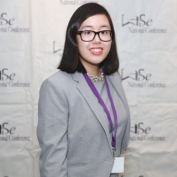 Linda Duong wearing a grey blazer with black-frame glasses.