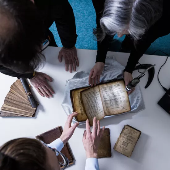 Researchers study a delicate old book