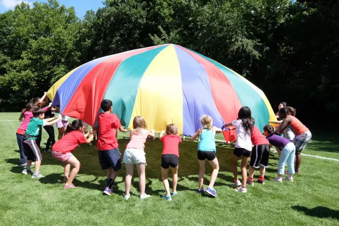 Children play with a parachute on a sunny summer day