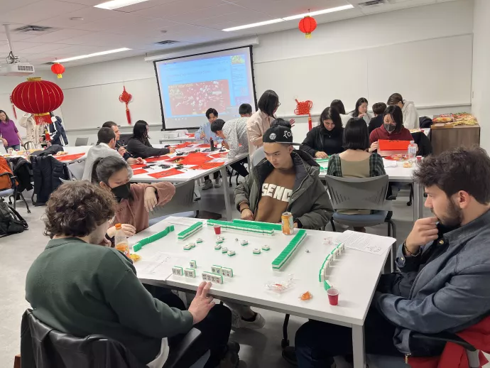 Students play mahjong while seated around a table