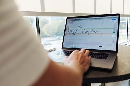 Person looking at stock market trend graph on a laptop