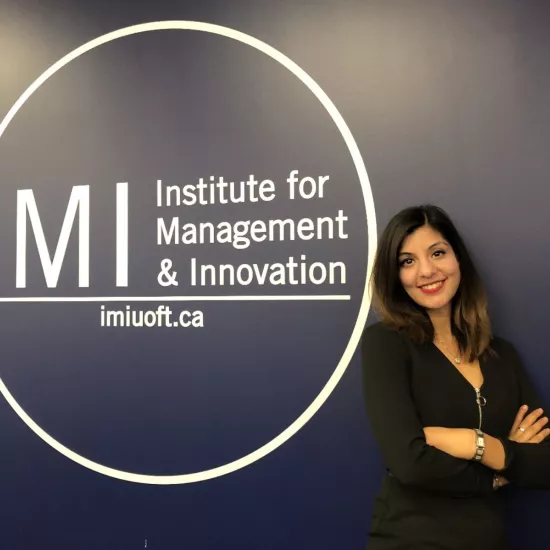 Natasha Walli standing in front of IMI Logo