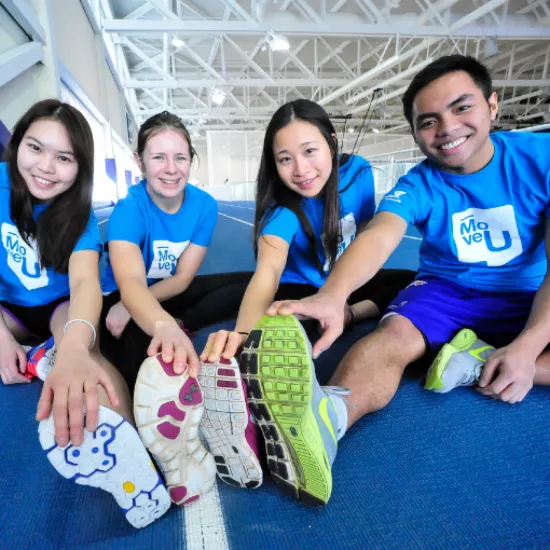 Four students in UTM Tshirts and running shoes stretch their legs