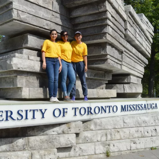 students standing on UTM main entrance sign