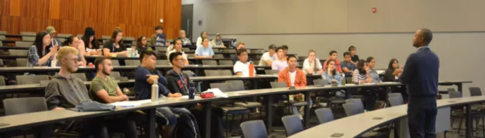 Professor lecturing students in a hall.