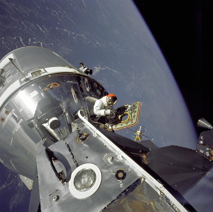 A spacecraft in space with Earth in the background and an astronaut exiting from a hatch. Image credit to NASA from https://www.nasa.gov/centers/marshall/history/this-week-in-nasa-history-apollo-9-splashes-down-march-13-1969.html. 