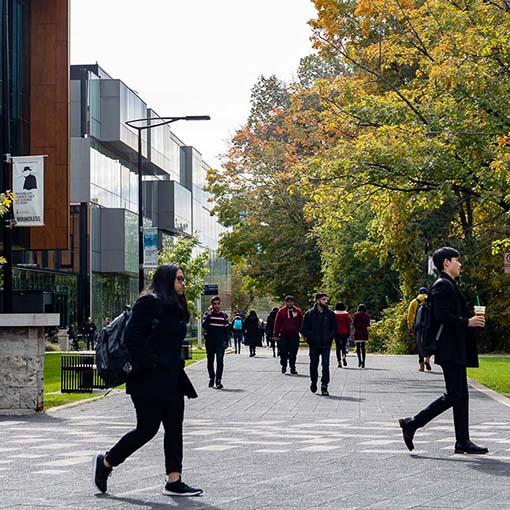 Students walking around the exterior of the Hazel McCallion Academic Learning Centre in the fall