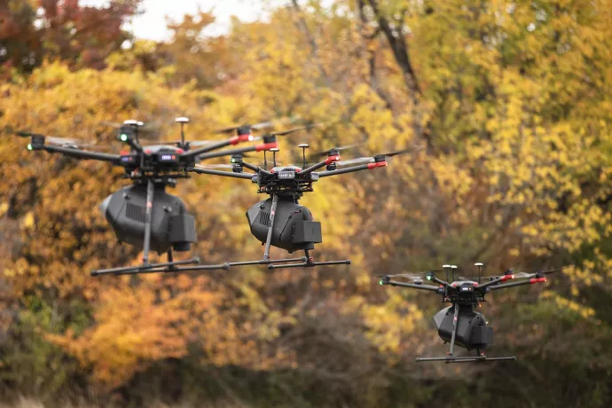 Three drones flying with autumn yellowed trees in the background