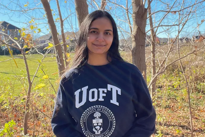 Neha Sharma stands in front of a tree wearing a UofT sweater.