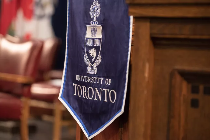 University of Toronto crest on flag draped over wooden podium in Convocation Hall