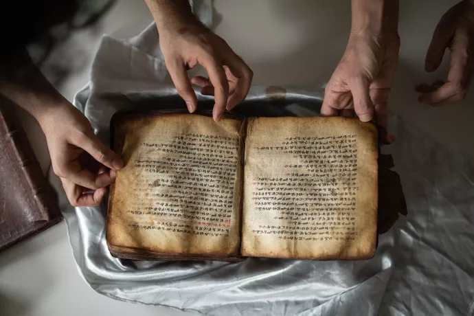 A medieval manuscript lies open and unwrapped on a table